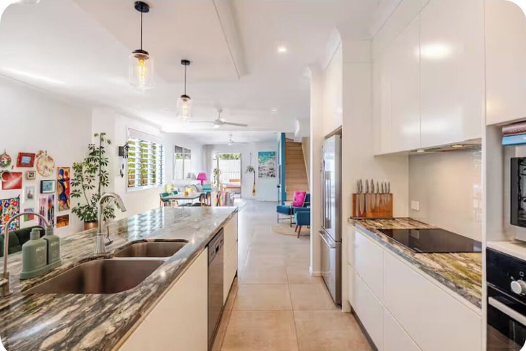 A modern kitchen with a central island, stainless steel appliances, and pendant lighting.
