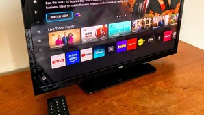 Ein Fernseher zeigt eine Sendung mit dem Titel 'Dragons’ Den', daneben liegt eine Fernbedienung.