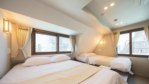 A hotel room with two beds, large windows, and built-in lighting.