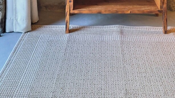 Una estantería de madera rústica con una cesta tejida, una lámpara colgante y una pared de piedra.