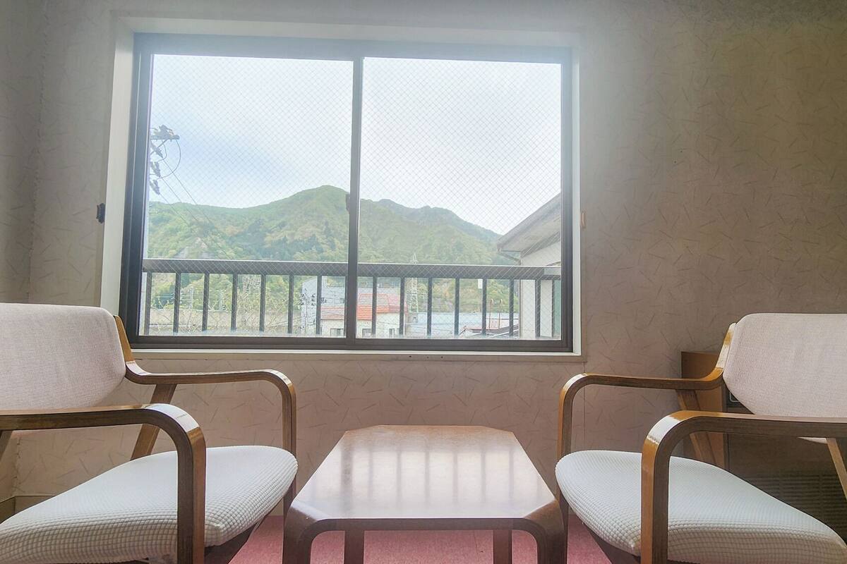 A room with a large window, two chairs, and a small table.