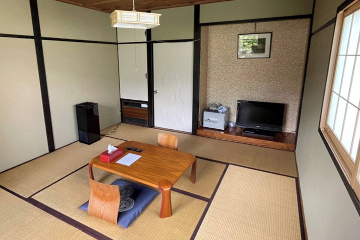 A traditional Japanese room with tatami flooring, a low table, a television, and a speaker.