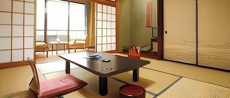 A tatami mat room with a low table, a chair, and a sliding door.