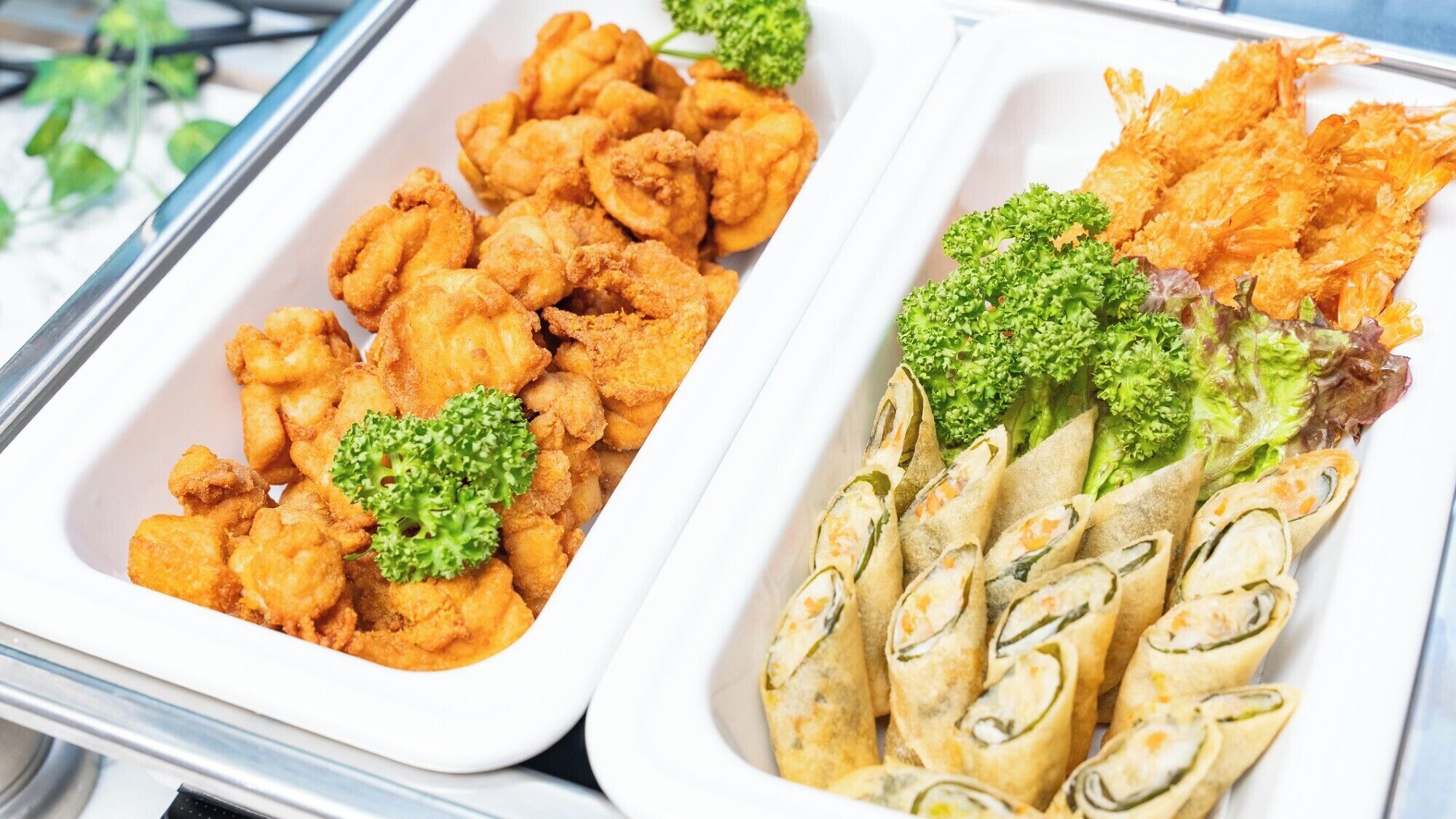 Ein Buffet mit verschiedenen Speisen, darunter frittierte Gerichte und Gemüse.