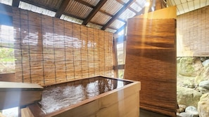 A traditional Japanese onsen with a wooden bath, bamboo walls, and a stone backdrop. - LiVEMAX RESORT Echigo Yuzawa ANNEX (Yuzawa)