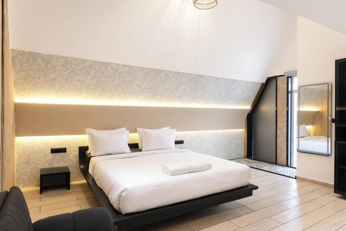 Une chambre à coucher moderne, avec un lit, des tables de chevet et un téléviseur encastré.