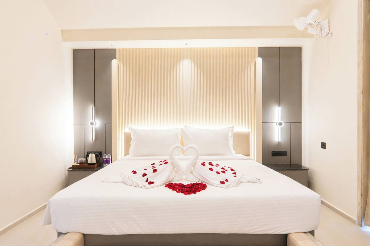 Une chambre d’hôtel avec un grand lit, des tables de chevet et des lampes fixées au mur.