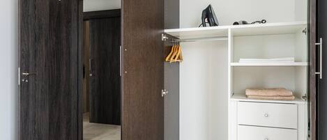 A bedroom with a wardrobe, a bed, and a bathroom visible through an open door.
