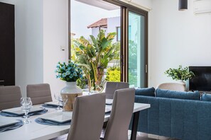 Un comedor con una mesa preparada para dos personas, un sofá y un televisor.