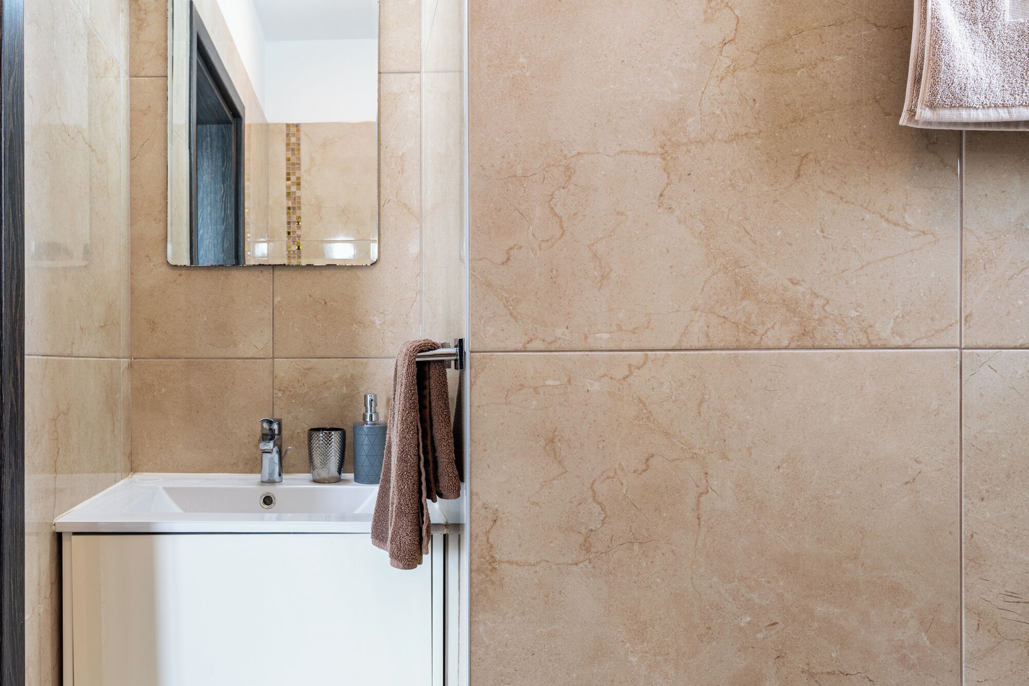 Une salle de bain équipée d’un lavabo, d’un miroir et d’un porte-serviettes.