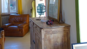 A room with a wooden cabinet, a green chair, a brown leather sofa, and a large framed picture on the wall. - House with river access and sauna at the foot of the château, La Flèche zoo and 24h (Durtal)