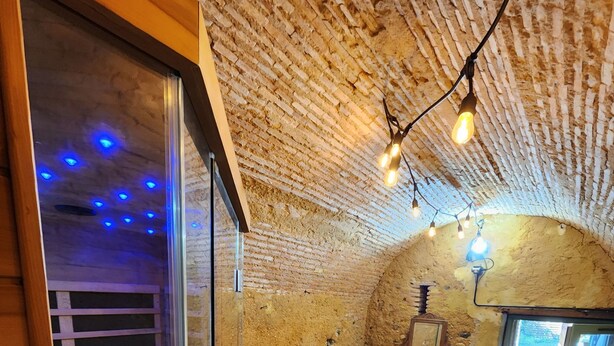A cozy room with a wooden floor, a sofa, a chair, and a small table. - House with river access and sauna at the foot of the château, La Flèche zoo and 24h (Durtal)