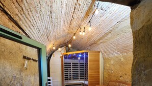 An underground room with a wooden bench, a white chair, and a wooden table. - House with river access and sauna at the foot of the château, La Flèche zoo and 24h (Durtal)