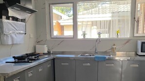 A modern kitchen with a gas stove, stainless steel cabinets, a microwave, and a window with a view of the outside.