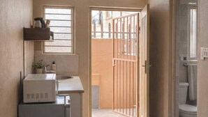 A compact kitchen with a window, a door leading to a balcony, and a view of the outside. - Cozy Private Studio Flat in Westdene, Johannesburg (Johannesburg)