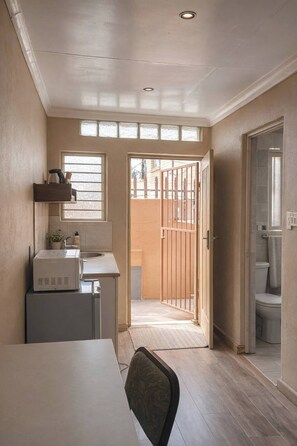 Cocina compacta con ventana, puerta que da a un balcón y vistas al exterior.