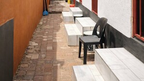 A narrow alleyway with a white building on the right, featuring red shutters and a small table with chairs. - Cozy Private Studio Flat in Westdene, Johannesburg (Johannesburg)