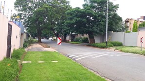 A residential street with houses, a zebra crossing, and a traffic sign. - Cozy Private Studio Flat in Westdene, Johannesburg (Johannesburg)