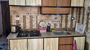 A kitchen with wooden cabinets, a gas stove, a sink, and a tiled backsplash. - Star Apartment 2 Hurghada (Hurghada)
