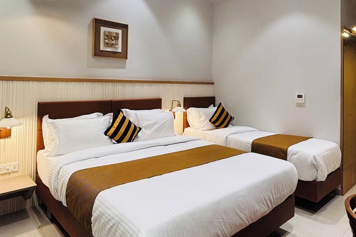 Ein modernes Hotelzimmer mit einem großen Bett, Deckenventilator, eingelassener Beleuchtung und einem gerahmten Bild an der Wand.