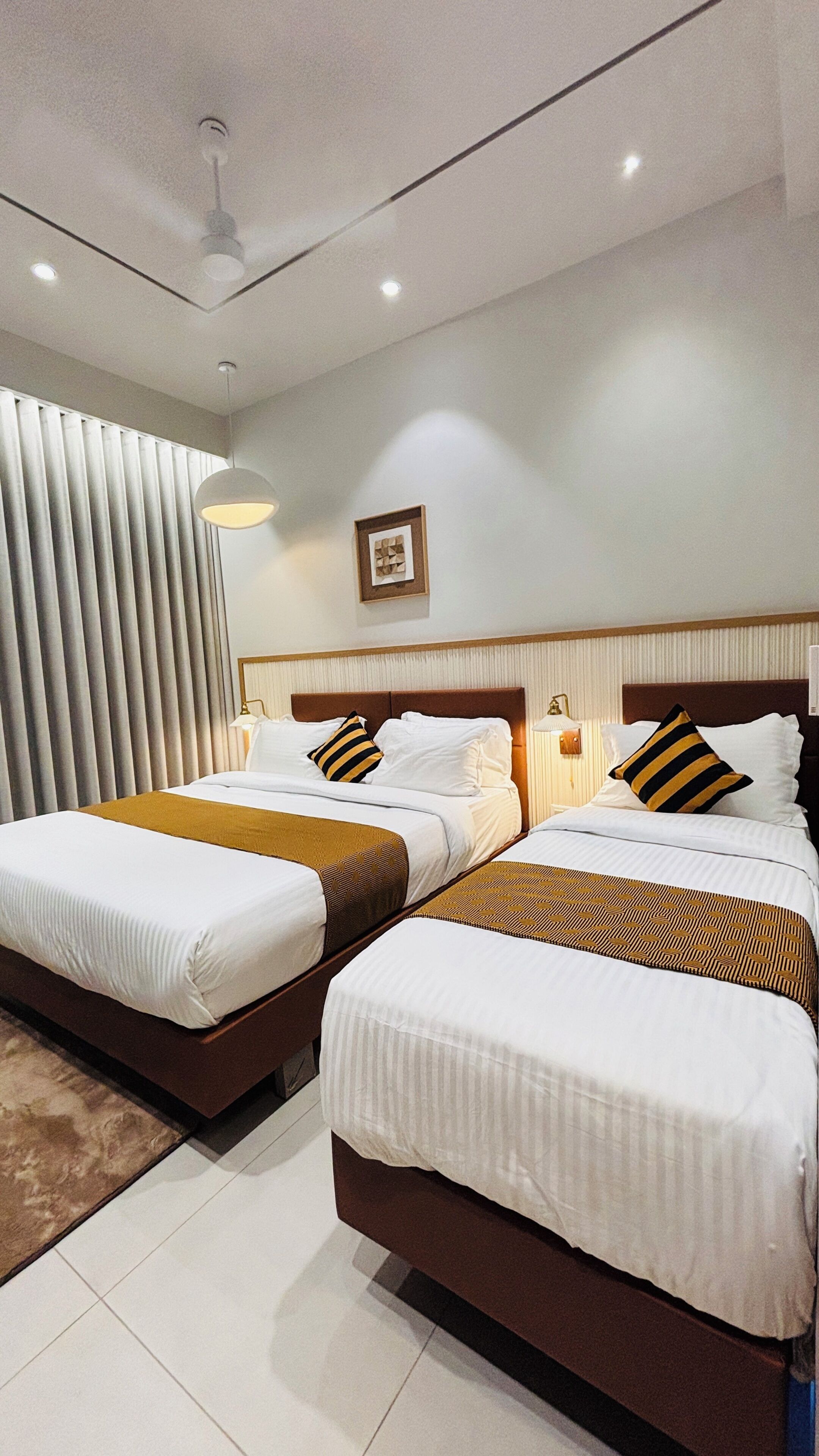 Ein Hotelzimmer mit zwei Betten, einem Deckenventilator und einem Fenster mit Jalousien.