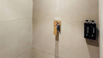 A modern bathroom with a shower, a towel rack, and a soap dispenser.