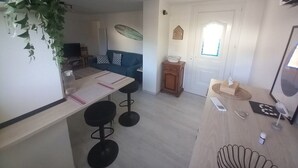 Kompakti keittiö, jossa on ruokailutila, pieni puinen kaappi ja ikkunallinen ovi.