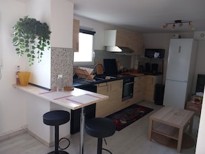 A compact kitchen with a central island, bar stools, a small dining table, and a refrigerator. - Rental Mimizan plage SUD- air-conditioned T4 ground floor + garden + wifi + parking- 4 pers (Mimizan)