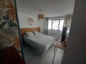 A bedroom with a bed, a television, a wall clock, and a window with curtains. - Rental Mimizan plage SUD- air-conditioned T4 ground floor + garden + wifi + parking- 4 pers (Mimizan)
