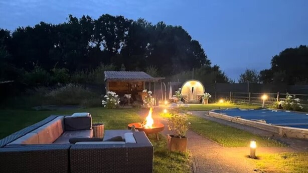 Une terrasse avec un canapé, un foyer extérieur et un petit abri de jardin.