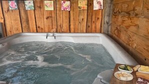 Een hottub met een houten wand en een houten terras, met eten erop.