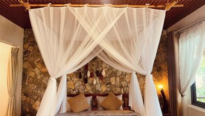 A bed with a canopy, stone wall, and a window with curtains. - The L'anmien Bui Vien (Ho Chi Minh City)