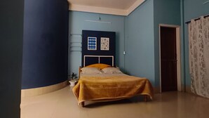 A bedroom with a bed, a ceiling fan, a door, and a wall-mounted shelf.