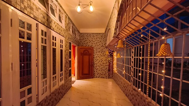 A corridor with tiled walls, a wooden door, and a window with string lights.