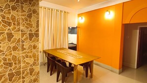 A dining area with a stone wall, a wooden table, and a ceiling fan.