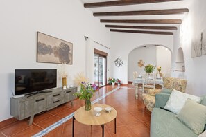 Uma sala de estar com televisão, mesa de jantar e sofá.
