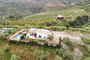 Uma villa com piscina, rodeada por vegetação exuberante e colinas.