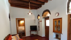 A cozy living room with a red sofa, wooden beams, a television, and a wooden table. - Country House 'Ktima Kariofillis' with Mountain View and Private Terrace (Révmata)