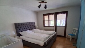 A bedroom with a bed, a nightstand, a chair, and a window.