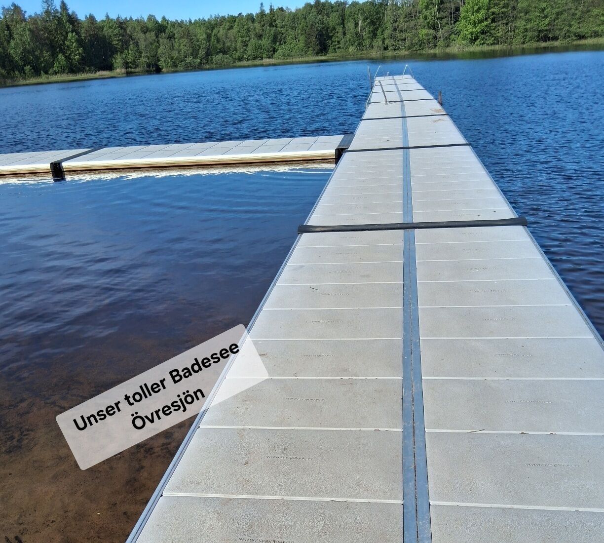 Un pilier de béton s’étendant dans une étendue d’eau, sur lequel est apposée une pancarte indiquant : « Unser Toller Badese Övrespänne. »