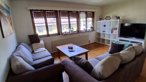 A living room with a sofa, a coffee table, a TV, and a bookshelf.