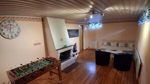 A room with a foosball table, a fireplace, a sofa, and a clock on the wall.