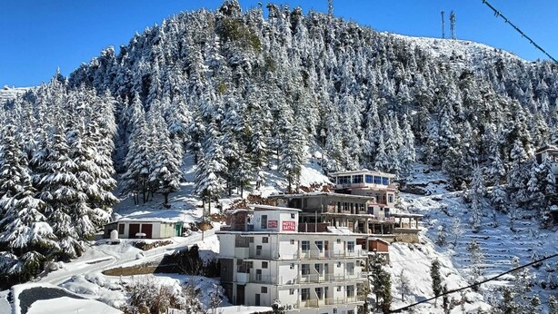 A hotel with multiple floors, a ski lift in the background, and a snowy mountainous landscape. - Hotel Satya (Chamba)