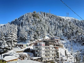 A hotel with multiple floors, a ski lift in the background, and a snowy mountainous landscape.