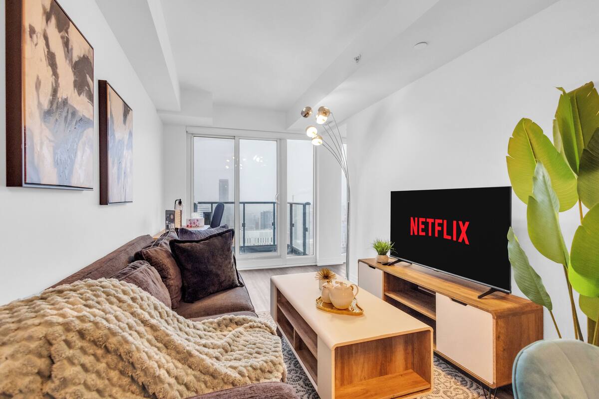 Una sala de estar moderna con sofá, mesa de centro y una televisión mostrando 'NETFLIX'.