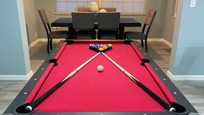 Une table de billard recouverte d’un feutre rouge, avec des bandes noires, et une bille blanche placée au centre.