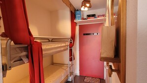A bunk bed room with a ladder, a small shelf with books, and a red curtain. - Cosy apartment, superb view at the foot of the slopes. (Selonnet)