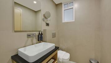 A modern bathroom with a large rectangular sink, a mirror, a small window, and a toilet.