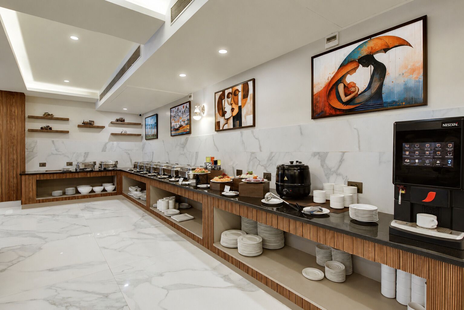 A modern hotel breakfast area with marble flooring, a buffet counter, and a Nescafé coffee machine.