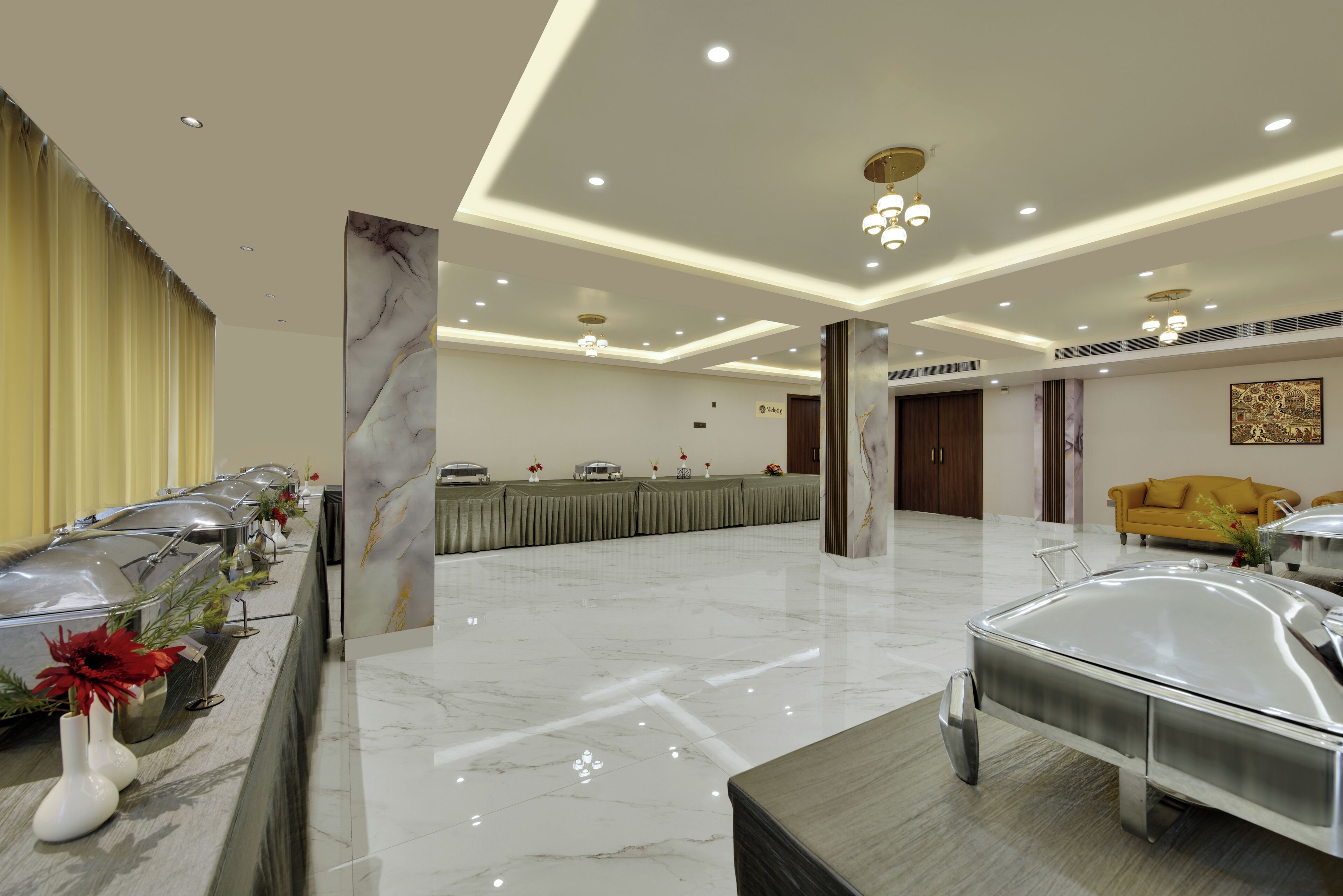 A hotel lobby with a long reception desk, a yellow sofa, and a marble floor.